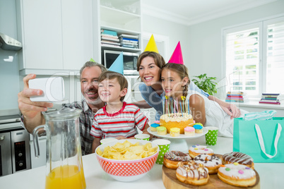 Happy family taking selfie on mobile phone in kitchen