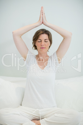 Woman doing meditation on bed in bedroom