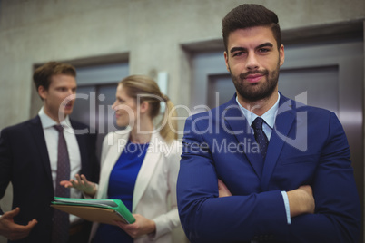 Portrait of handsome businessman standing with arms crossed