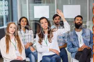 Female executive raising hand during presentation