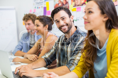 Portrait of smiling executive working on laptop in conference room with colleague