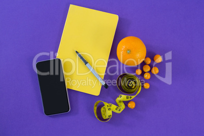 Mobile phone, book, pen, measuring tape and citrus fruit