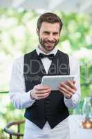 Male waiter holding digital tablet