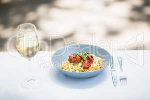 Wine glass with food in bowl and cutlery arranged on table
