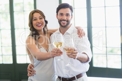 Happy couple hugging while toasting wine glasses