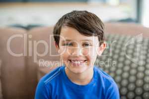 Portrait of smiling boy sitting on sofa in living room