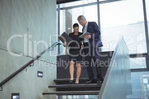 Business executives discussing over digital tablet on stairs