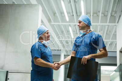 Male surgeons holding x-ray while shaking hands