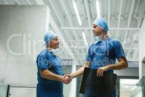 Male surgeons holding x-ray while shaking hands