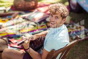 Portrait of happy man playing guitar in park