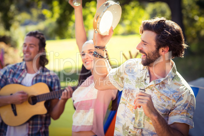 Man holding beer bottle and playing tambourine