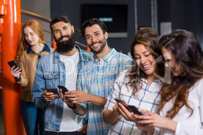 Happy male and female executive using mobile phone in office