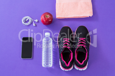 Sneakers, water bottle, towel, mobile phone with headphones and apple