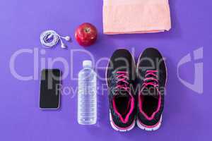 Sneakers, water bottle, towel, mobile phone with headphones and apple