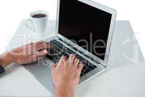 Businessman using laptop while having coffee