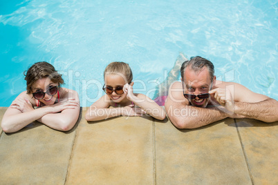 Happy parents and daughter relaxing in pool