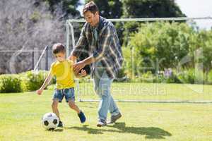Father and son playing football in the park
