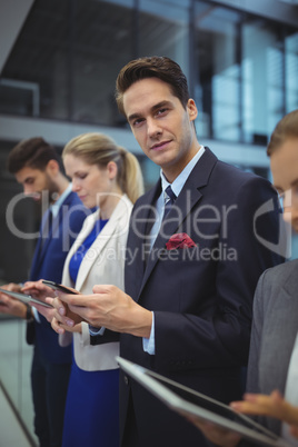 Business executives using electronic devices in corridor