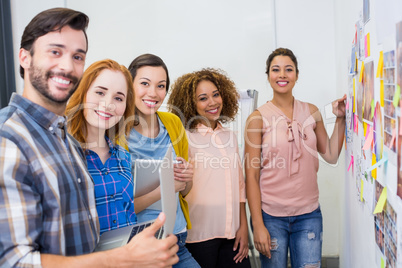 Portrait of smiling executives discussing over sticky notes during meeting