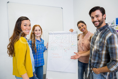 Smiling executives discussing over flip chart board in conference room meeting