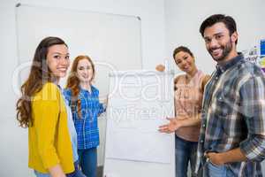 Smiling executives discussing over flip chart board in conference room meeting