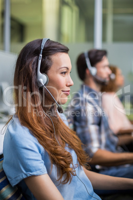 Smiling female customer service executive talking on headset at desk