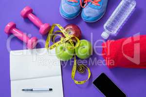 Fitness accessories with opened book, apples, mobile phone and measuring tape