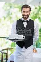 Male waiter holding tray with coffee cups