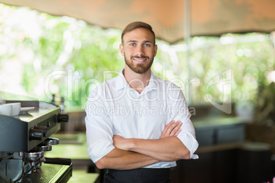 Waiter standing with arms crossed at restaurant
