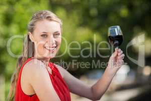 Beautiful woman holding glass of wine in the park