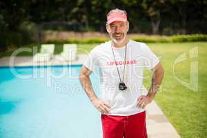 Portrait of swim coach with stopwatch standing with hands on hip near poolside