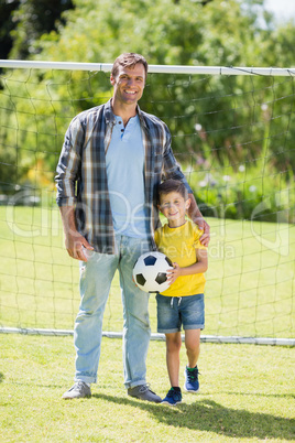 Father and son with football in the park on a sunny day