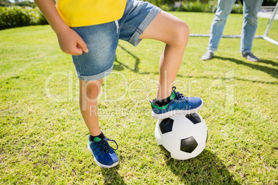 Low section of boy with leg on football