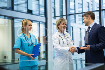 Female doctor shaking hands with businessman
