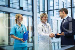Female doctor shaking hands with businessman