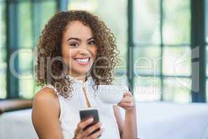 Beautiful woman holding coffee cup and using mobile phone