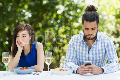 Man ignoring woman and using mobile phone