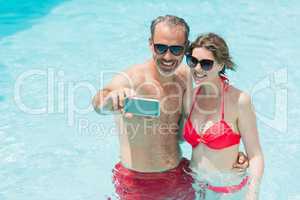 Happy couple taking selfie from mobile phone in pool