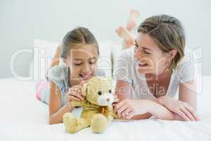 Mother and daughter lying on bed in bedroom at home