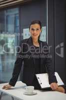 Businesswoman with clipboard sitting on the desk at office