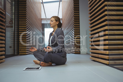 Businesswoman performing yoga in the corridor