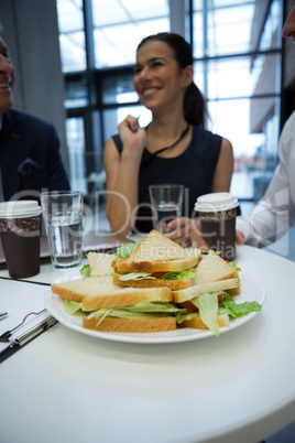 Close-up of breakfast on table with businesspeople in background