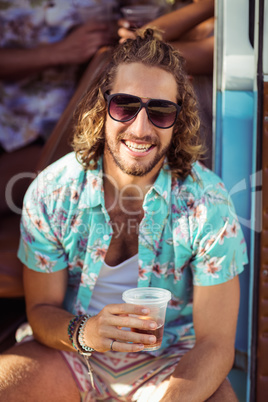 Portrait of happy man sitting in campervan with glass of beer