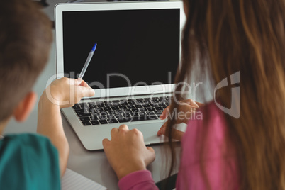 School kids using laptop in library