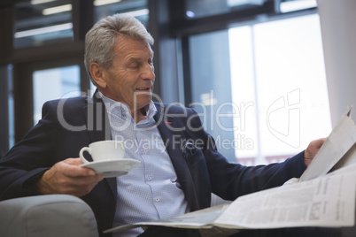 Businessman reading newspaper while having coffee