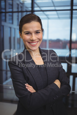 Portrait of beautiful businesswoman standing with arms crossed in corridor