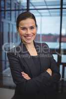 Portrait of beautiful businesswoman standing with arms crossed in corridor