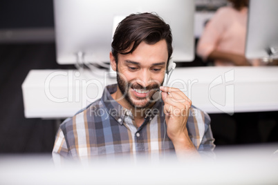 Smiling male customer service executive talking on headset at desk