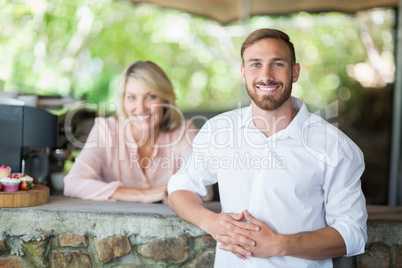 Waiter and customer standing at counter at restaurant