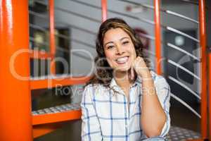 Smiling female executive sitting on staircase in office